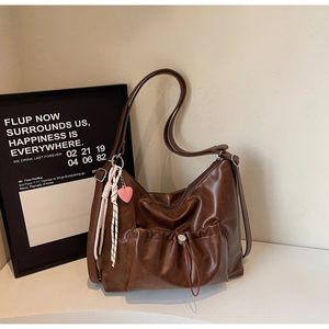 Close-up of brown faux leather hobo bag with drawstring pocket and heart charm detail