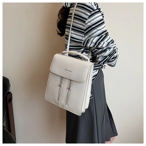 Détail d'un sac à dos blanc en cuir grainé avec double fermeture éclair et logo chic