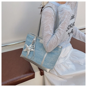 Detail of light blue tote bag with silver leather trim and a silver star pendant accessory