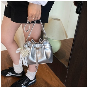Detail der silbernen Metallic-Beuteltasche mit Perlenherz-Anhänger und Kordelzugkette