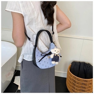 Détail du sac croissant bleu clair avec nœud noir et breloque ours en peluche blanc