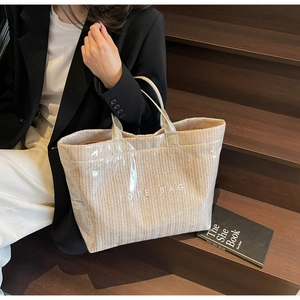 Detail of woven tote bag with PVC outer layer and white TOTE BAG text shown on stairs