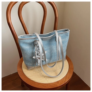 Detail of light blue denim tote bag with silver star charm on a vintage wooden chair
