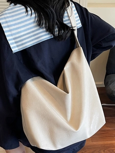 Cream soft leather bucket shoulder bag with glossy wrinkled texture for daily commute