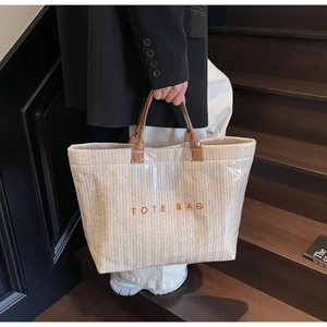 Detail of woven straw tote bag with clear PVC coating and sturdy brown leather handles