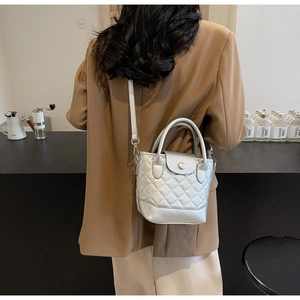 Close-up of silver quilted bucket bag with metallic texture and snap button closure