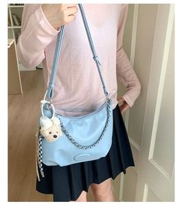 Detail of light blue hobo bag with silver chain and cute teddy bear charm accessory