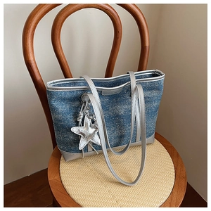 Detail of blue denim tote bag with shimmering finish and silver star charm accessory