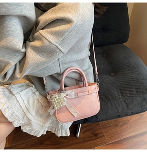 Detail of light pink bag featuring a heart pearl pendant and a white lace bow detail