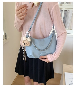 Detail of light blue crescent shoulder bag with silver chain and cute bear charm accent