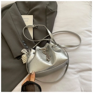 Nahaufnahme der silbernen Beuteltasche mit Faltenstruktur, Metallkette und Perlenanhänger