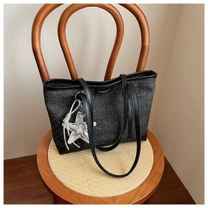 Detail of black polka dot tote bag featuring a silver star pendant and long leather handles