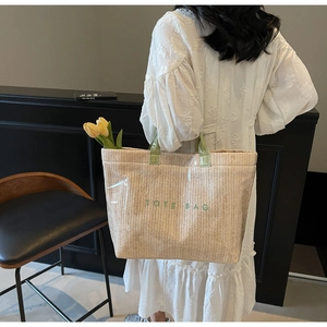 Close-up of beige woven tote bag with green embroidered text and yellow tulips inside