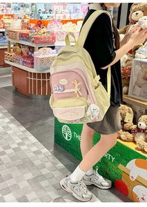 Detailed shot of yellow and pink school backpack with cute badge and plush charms