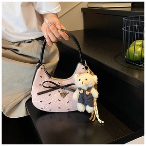Détail du sac croissant en jacquard rose avec nœud en cuir noir et breloque ours