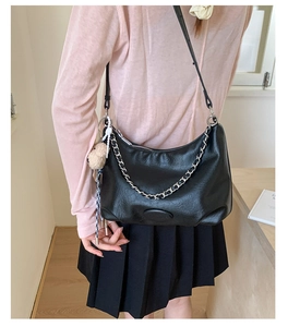 Detail of black faux leather hobo bag with silver chain and cute plush animal charm