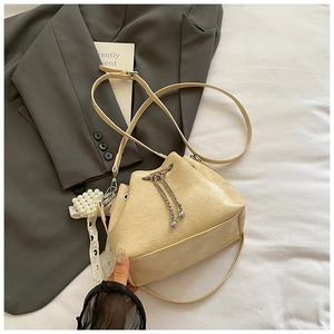 Detail der beige Beuteltasche mit silberner Kette und elegantem Perlen-Spitzenanhänger