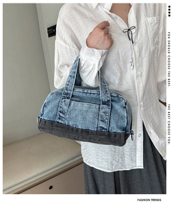 Detail of a denim handbag showing contrast patchwork design and sturdy top handle strap
