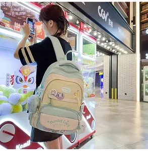 Detail of mint green school backpack with badge, plush bear charm and side coin pouch