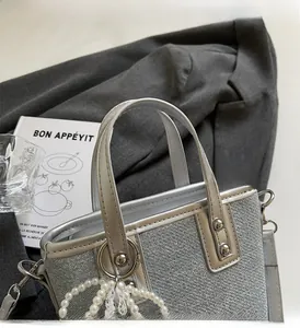 Detail einer hochwertigen silbernen Eimertasche mit Perlen- und Spitzenanhängern