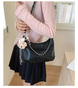 Detail of black crescent shoulder bag with silver chain and cute brown plush bear charm