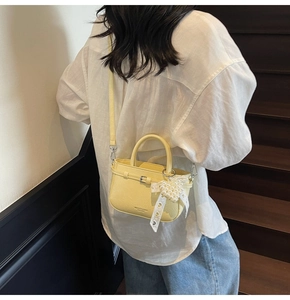 Detailed view of yellow leather tote with pearl bow charm and detachable strap