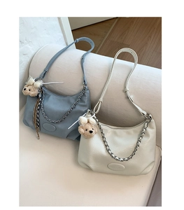 Detail of half-moon shoulder bags in blue and white with silver chain and bear charm