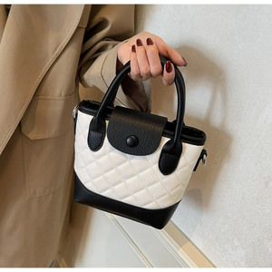 Detailed macro view of bicolor quilted bucket bag with contrast black lychee leather and studs