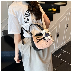 Détail du sac à bandoulière rose et noir avec imprimé floral et breloque ours en peluche