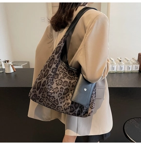 Close-up of leopard print tote bag with black leather pouch on a fashion model