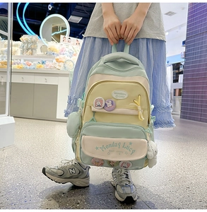 Close-up of mint green school backpack with cute rabbit pins and plush dog pendant
