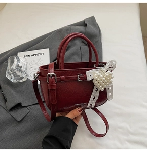 Close-up of a burgundy vintage handbag with white lace bow and pearl decoration