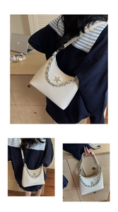 Détail du sac demi-lune blanc plissé avec étoile dorée et chaîne argentée