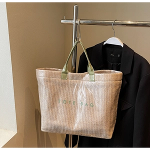 Detailed macro view of woven straw tote bag with clear PVC coating and green handle