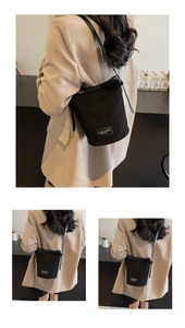 Detail der minimalistischen schwarzen Bucket Bag aus Mattleder mit Label und Umhängeriemen