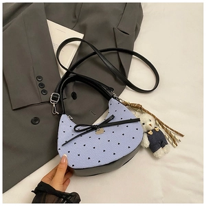 Détail du sac croissant à rayures bleues avec nœud noir et pendentif d'ours en peluche