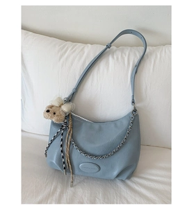 Detail of light blue crescent tote bag with silver chain and plush bear charm decoration