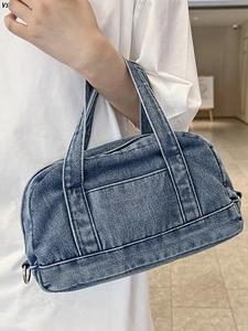 Vintage blue denim handbag with white stitching and double handles shown in hand
