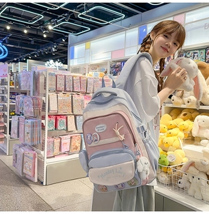 Detail view of pink and blue school backpack with cute cartoon badges and plush bunny keychain