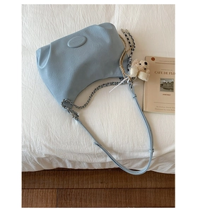 Detail of light blue textured leather tote bag with silver chain and cute bear charm decoration