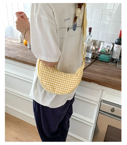 Detail of yellow gingham dumpling bag worn as a crossbody purse in a lifestyle setting
