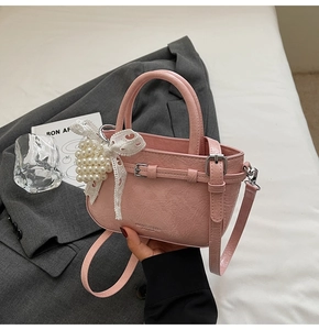 Pink pleated handbag detail with pearl heart and lace bow charm on silver hardware