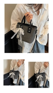 Detail der grauen Tweed-Beuteltasche mit weißer Spitzenschleife und Perlenanhänger am Griff