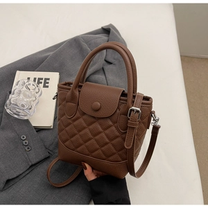 Detailed view of dark brown quilted leather handbag with silver hardware and dual handles