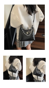 Détail du sac hobo en similicuir brillant noir avec étoile argentée et chaîne
