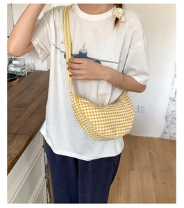 Detail of yellow and white checkered croissant bag worn by model in a casual side view