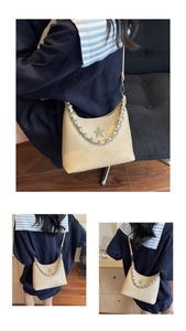 Détail du sac à bandoulière plissé beige avec emblème étoile et poignée chaîne argent