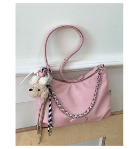 Detail of light pink leather shoulder bag with silver chain and cute teddy bear charm