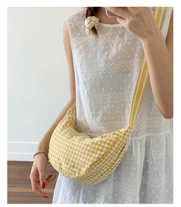 Detail of checkered canvas dumpling bag with striped wide shoulder strap in yellow and white