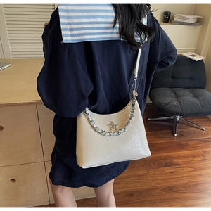 Détail d'un sac à bandoulière en cuir verni plissé blanc crème avec chaîne et étoile en strass